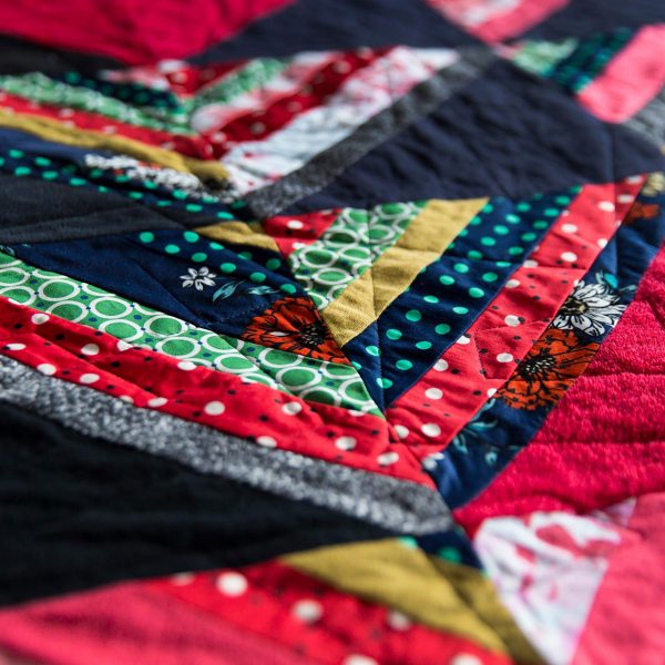 a close up detail of a few quilt blocks. There are black half square triangles alternating with strips of color, also sewn into half square triangles.