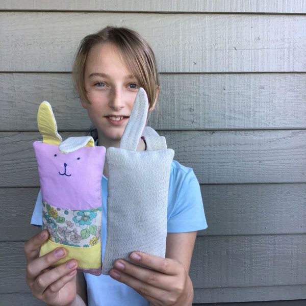 young girl holds two patchwork bunnies. One faves front so you can see the pink and yellow patchwork. The other faces back and you can see the scraps of baby blanket.