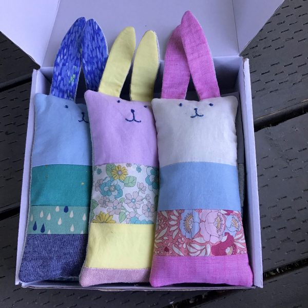 three patchwork stuffed bunnies in shades of blue, pink and yellow.